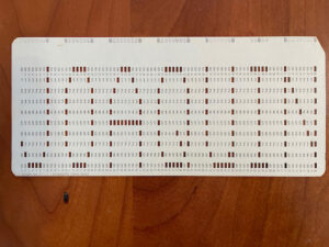 Punchcard with a pattern of holes that says JOAQUIN